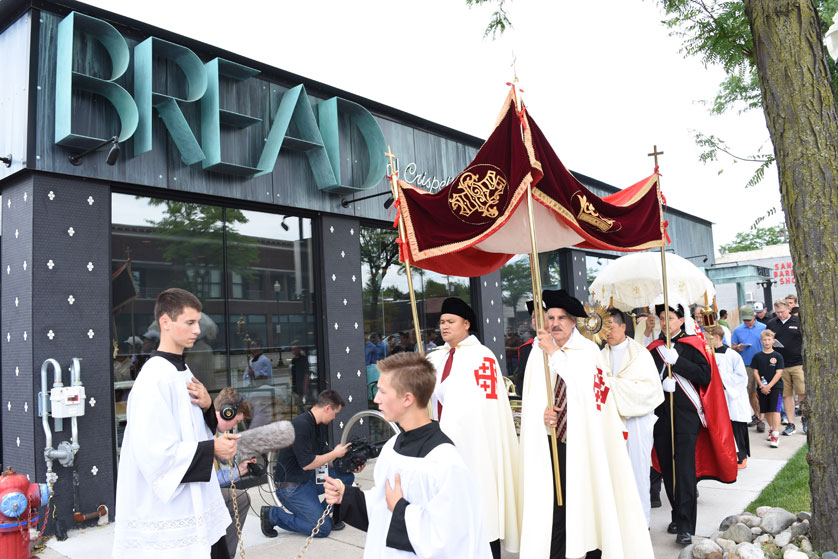 A Eucharistic procession passes by a bread shop in downtown Royal Oak as more than 600 men and their families walked behind the “Bread from Heaven” July 16 from the National Shrine of the Little Flower Basilica to St. Mary Parish.  Mike Stechschulte | The Michigan Catholic